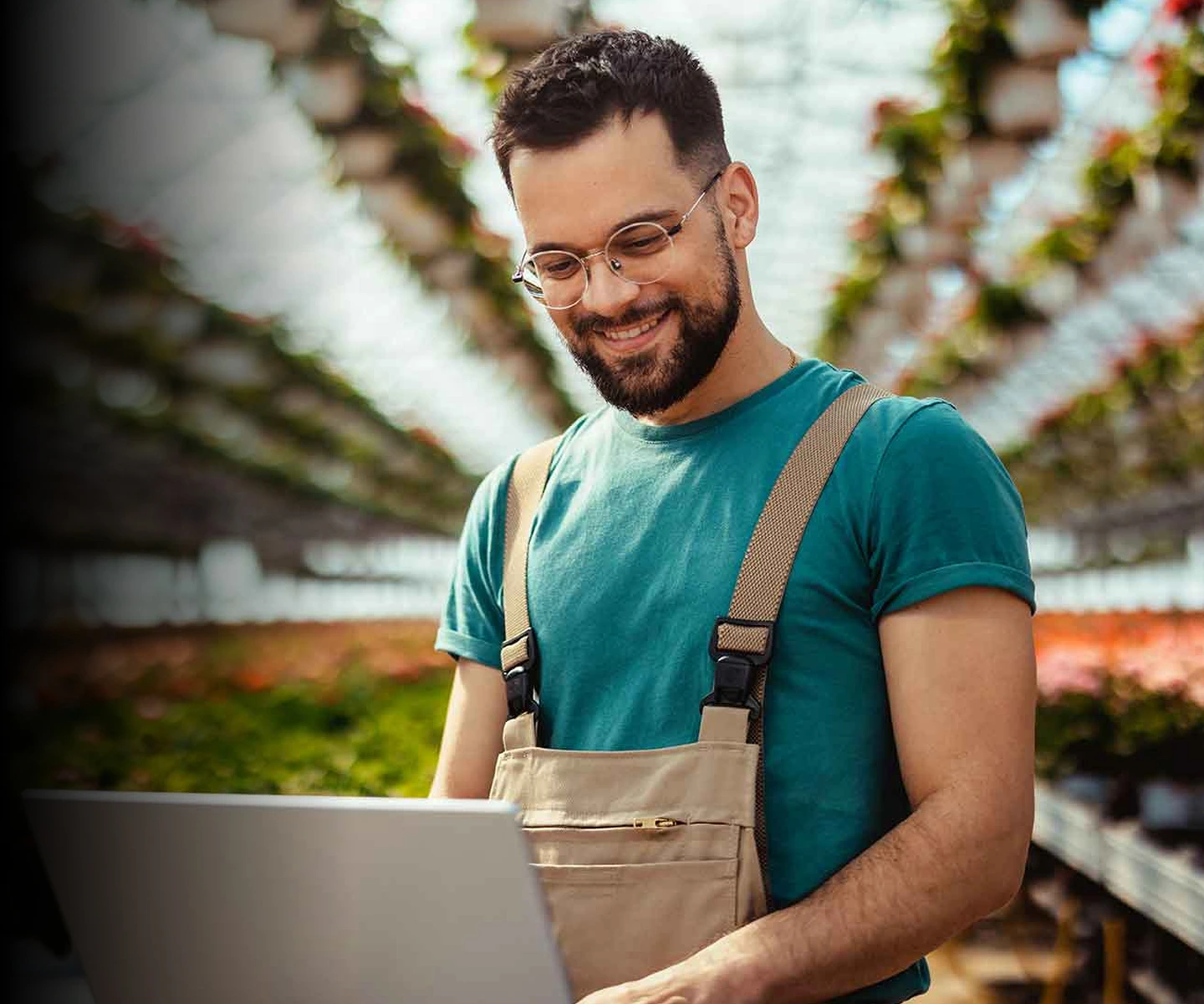 A man in overalls and glasses using a laptop